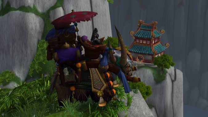 A transmog mount sits atop a rounded peak, with a Pandaren building in the background.